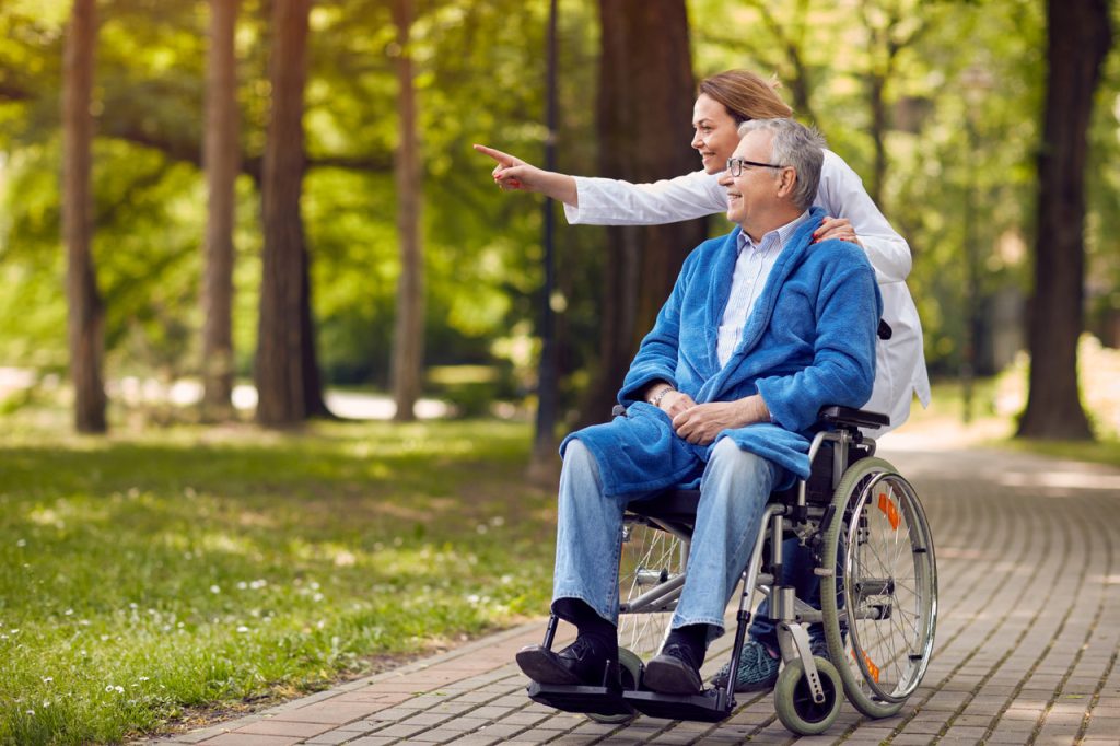 Woman pushing man in wheelchair out in nature