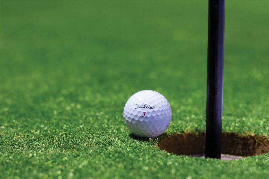 Stock photo of golf ball near the cup.
